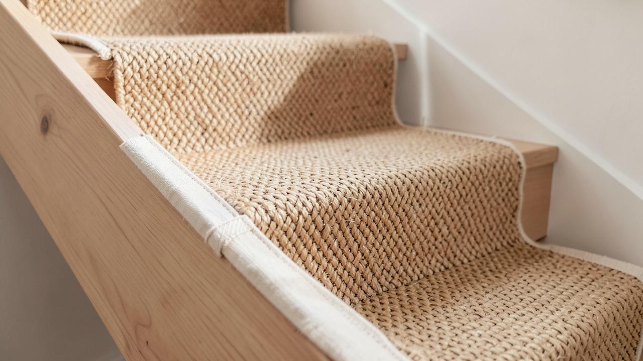 A natural sisal stair runner with a bound cotton border on light timber stairs